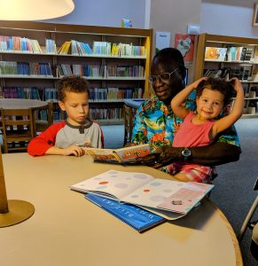 Image: A grandfather reads books to his grandchildren at the library